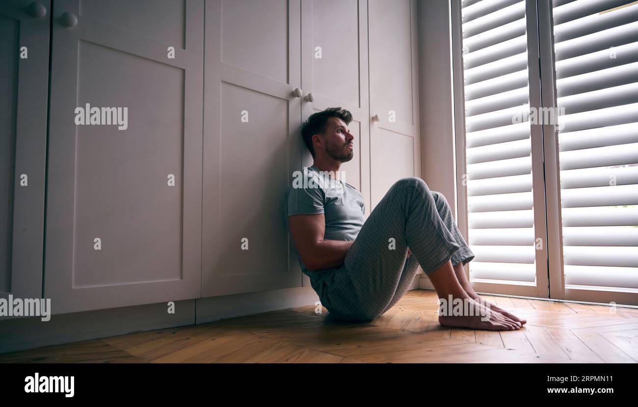 Depressiver Mann, Der Mit Schlechter Psychischer Gesundheit Leidet, Sitzt Zu Hause Auf Dem Boden Stockfoto