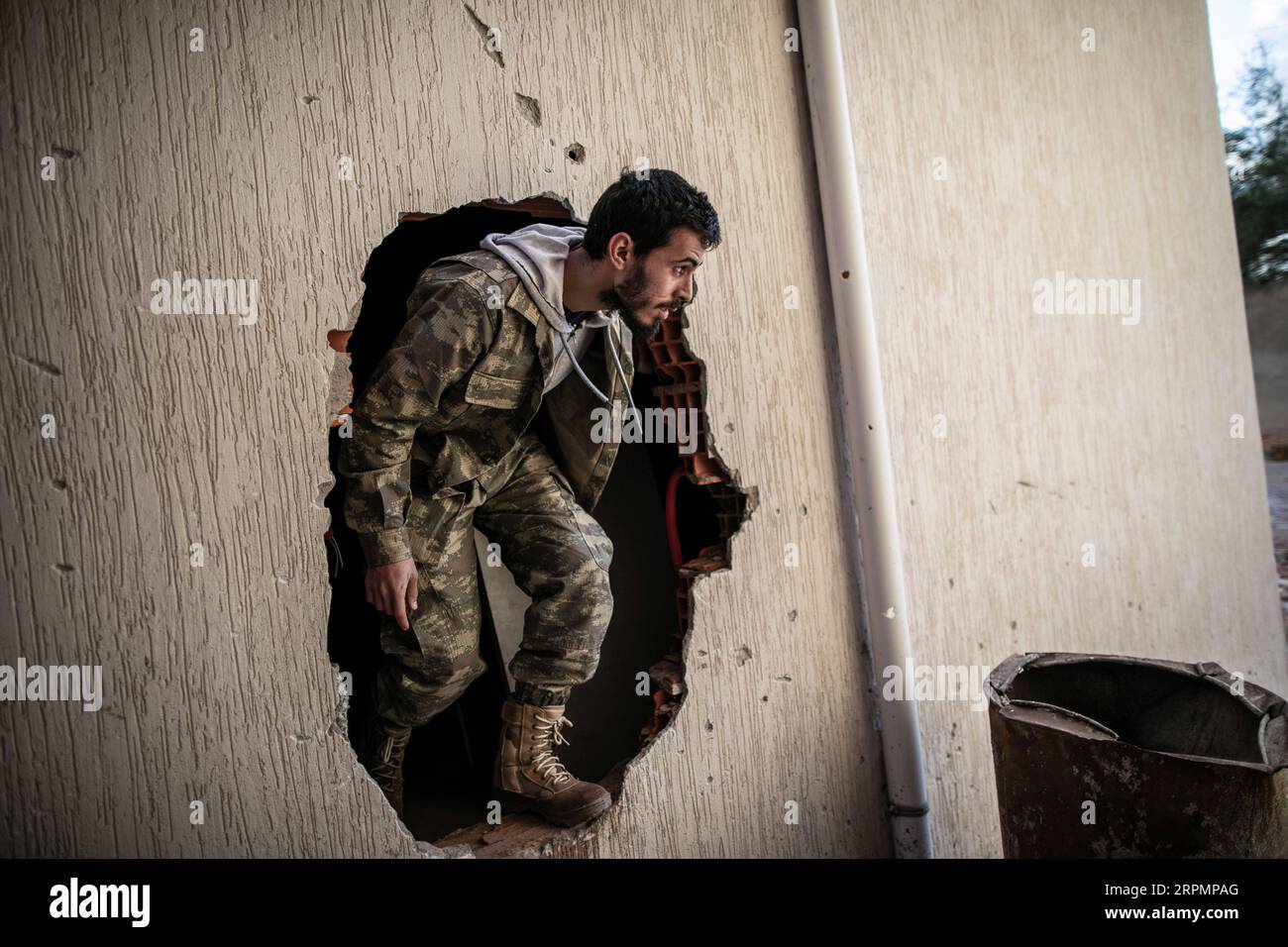 200215 -- TRIPOLI, 15. Februar 2020 Xinhua -- Ein Kämpfer der von den Vereinten Nationen unterstützten libyschen Regierungstruppen durchquert ein Loch in einem Gebäude während der Zusammenstöße mit LNA-Truppen der libyschen Nationalarmee an der Salah Al-DIN-Frontlinie in Tripoli, Libyen, am 15. Februar 2020. Foto von Amru Salahuddien/Xinhua LIBYA-TRIPOLI-CONFLICT-FRONTLINE PUBLICATIONxNOTxINxCHN Stockfoto