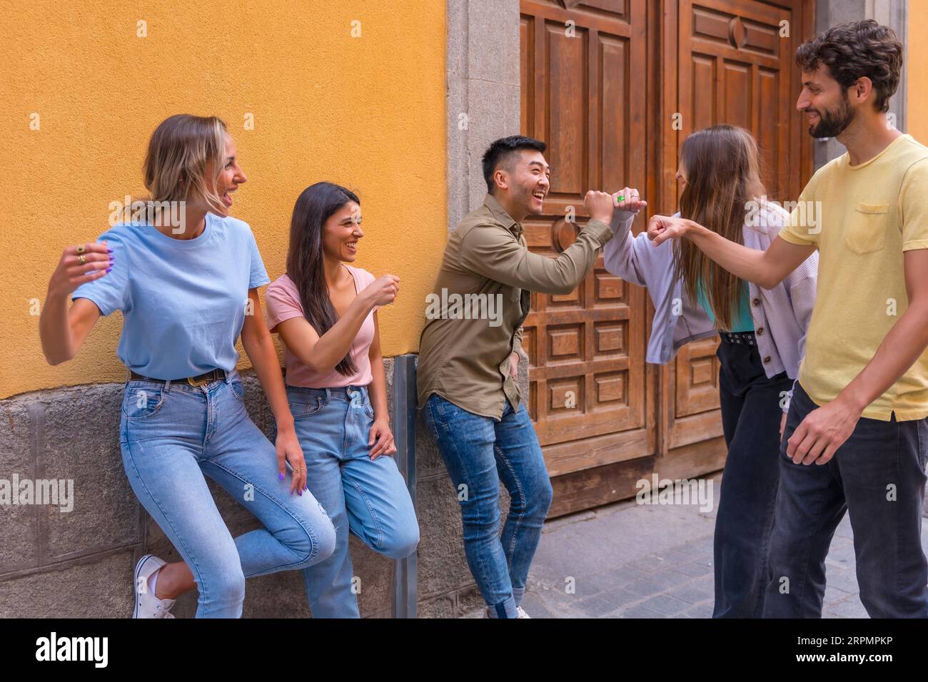 Eine Gruppe von multirassischen Freunden, die in der Stadt winken, ein Freundschaftskonzept mit Jungs und Mädchen, die in der Straße herumhängen Stockfoto