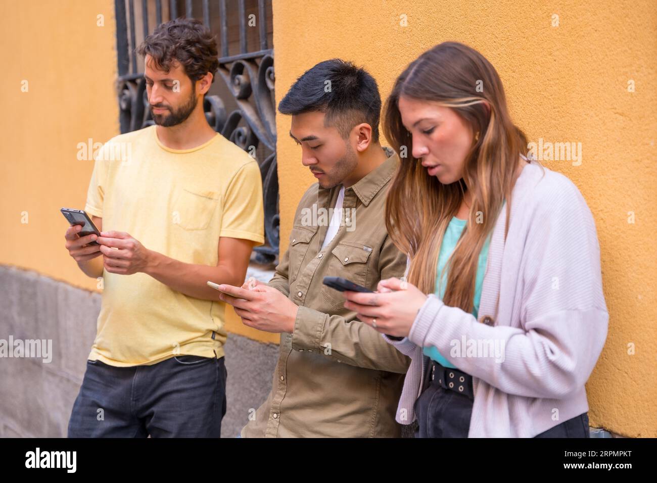 Eine Gruppe von Freunden aus verschiedenen ethnischen Gruppen, die ernsthaft am Telefon in der Stadt interessiert sind Stockfoto