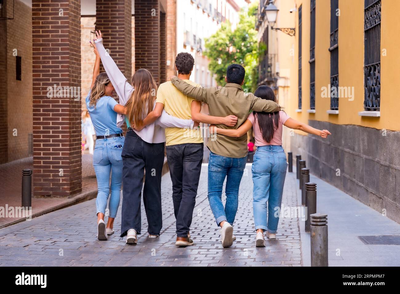 Eine Gruppe von multirassischen Freunden, die sich von hinten in der Stadt umarmen, Freundschaftskonzept mit Jungen und Mädchen Stockfoto