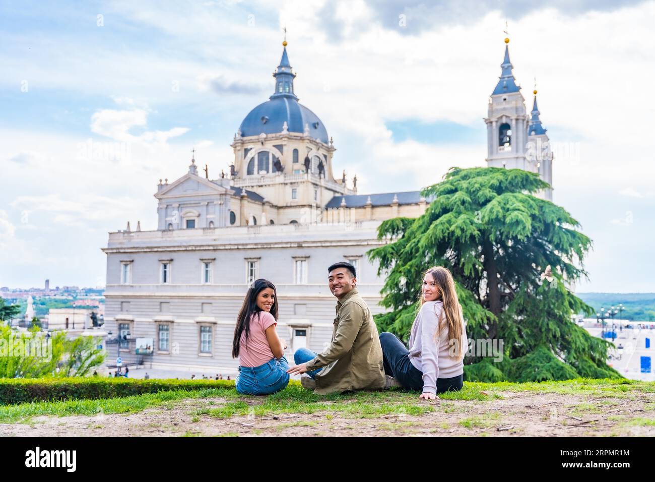 Porträt von Touristenfreunden, die Madrid im Sommerurlaub besuchen. Sitzen und auf die Almudena schauen Stockfoto