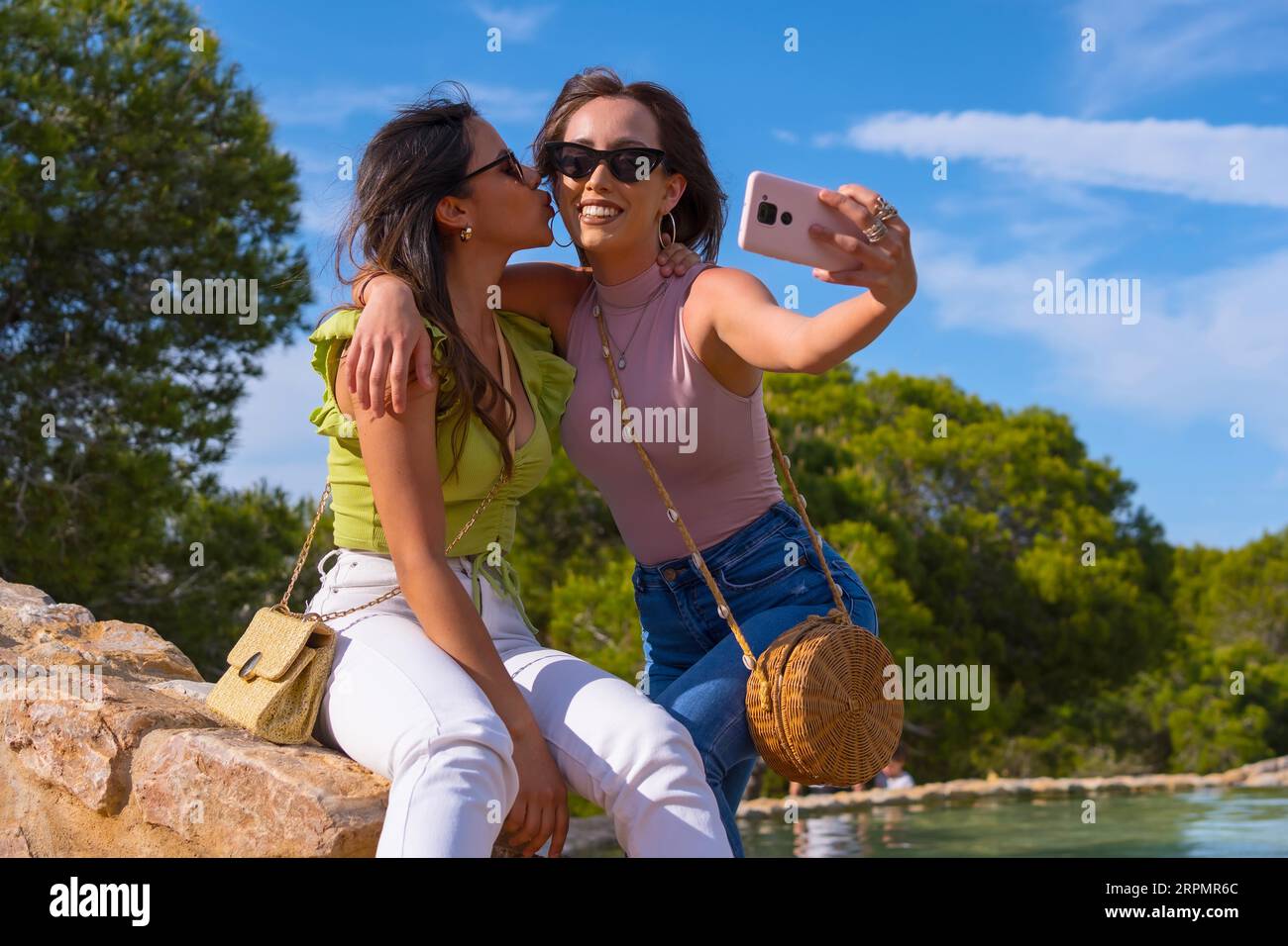 Kaukasische Freundinnen, die lächeln und ein Selfie mit dem Telefon im Sommerurlaub in einem Park machen Stockfoto
