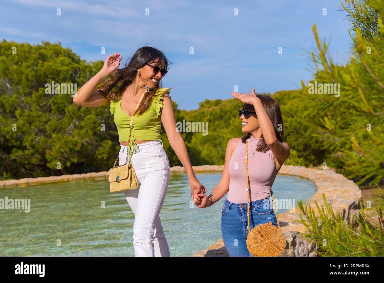 Freundinnen haben Spaß im Urlaub in einem Park im Sommer, laufen sehr glücklich neben einem See Stockfoto