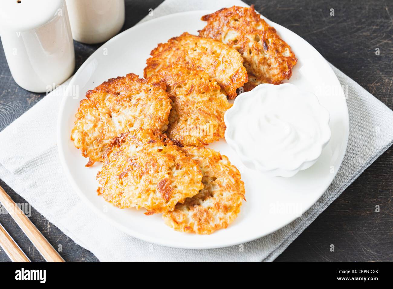 Kartoffelpfannkuchen oder Latkes oder Draniki mit saurer Sahne. Ukrainisches Essen. Ein geriebenes Kartoffelgericht mit Deruny oder Draniki Stockfoto