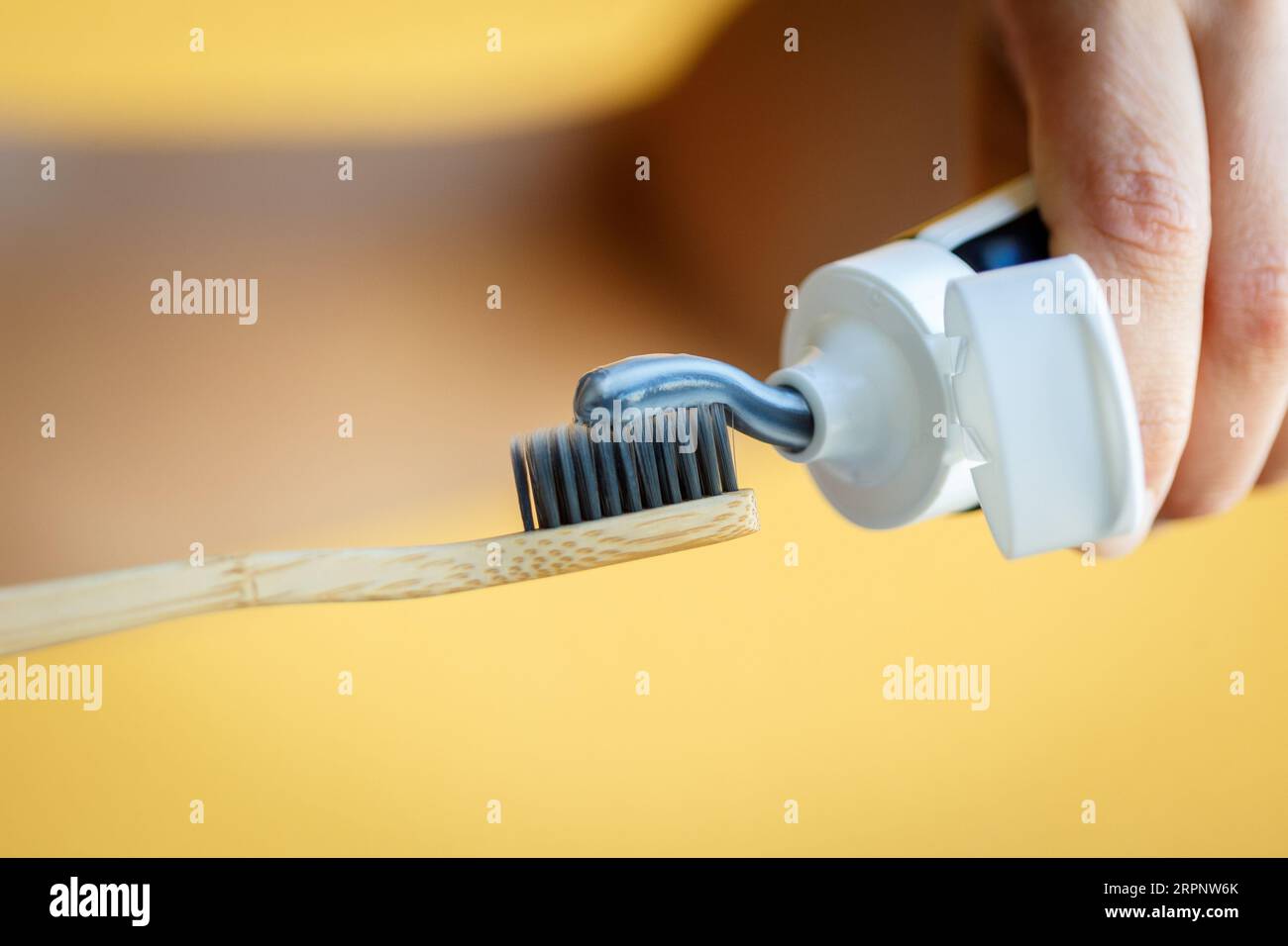 Zahnpasta auf eine Bambuszahnbürste auftragen. Zahnheilkunde und Hygenkonzept. Stockfoto