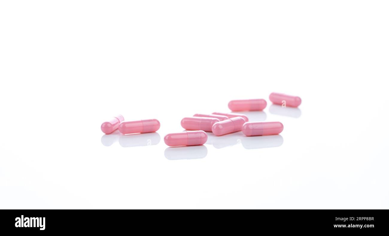 Rosafarbene Kapseltabletten auf weißem Hintergrund. Pharmazeutische Industrie. Konzept für Vitamine, Mineralstoffe und Nahrungsergänzungsmittel. Pharmazeutische Produkte. Pharmazeutischer Sanitäter Stockfoto