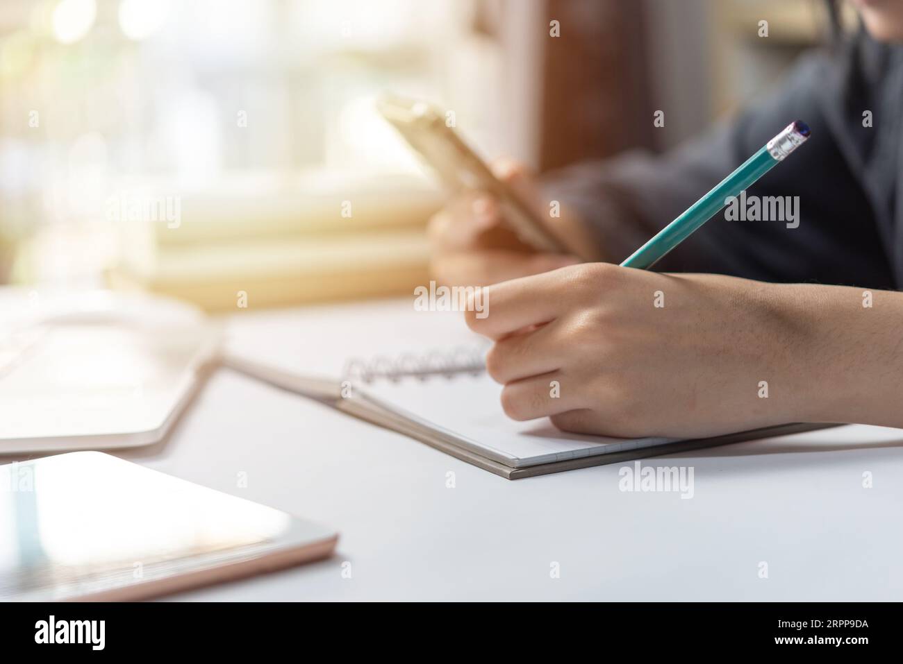 Frauenhand mit Bleistiftschrift auf Notizbuch. Stockfoto