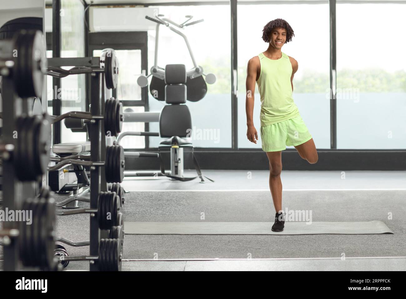 Portrait eines afroamerikanischen jungen Mannes in Sportkleidung, der das Bein im Fitnessstudio dehnt Stockfoto
