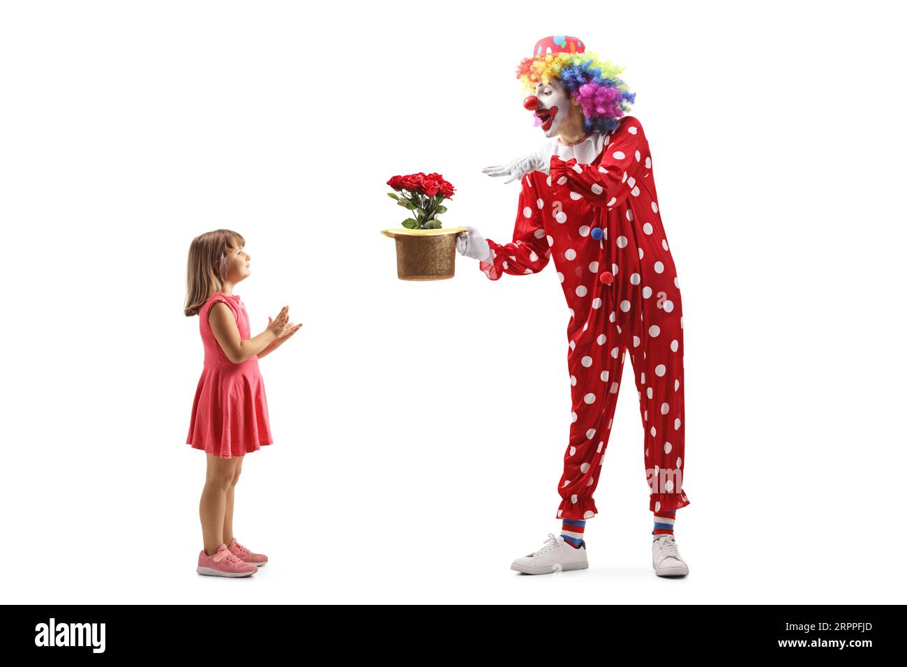 Profilaufnahme in voller Länge eines Mädchens, das einem Clown einen Zaubertrick auf weißem Hintergrund applaudiert Stockfoto