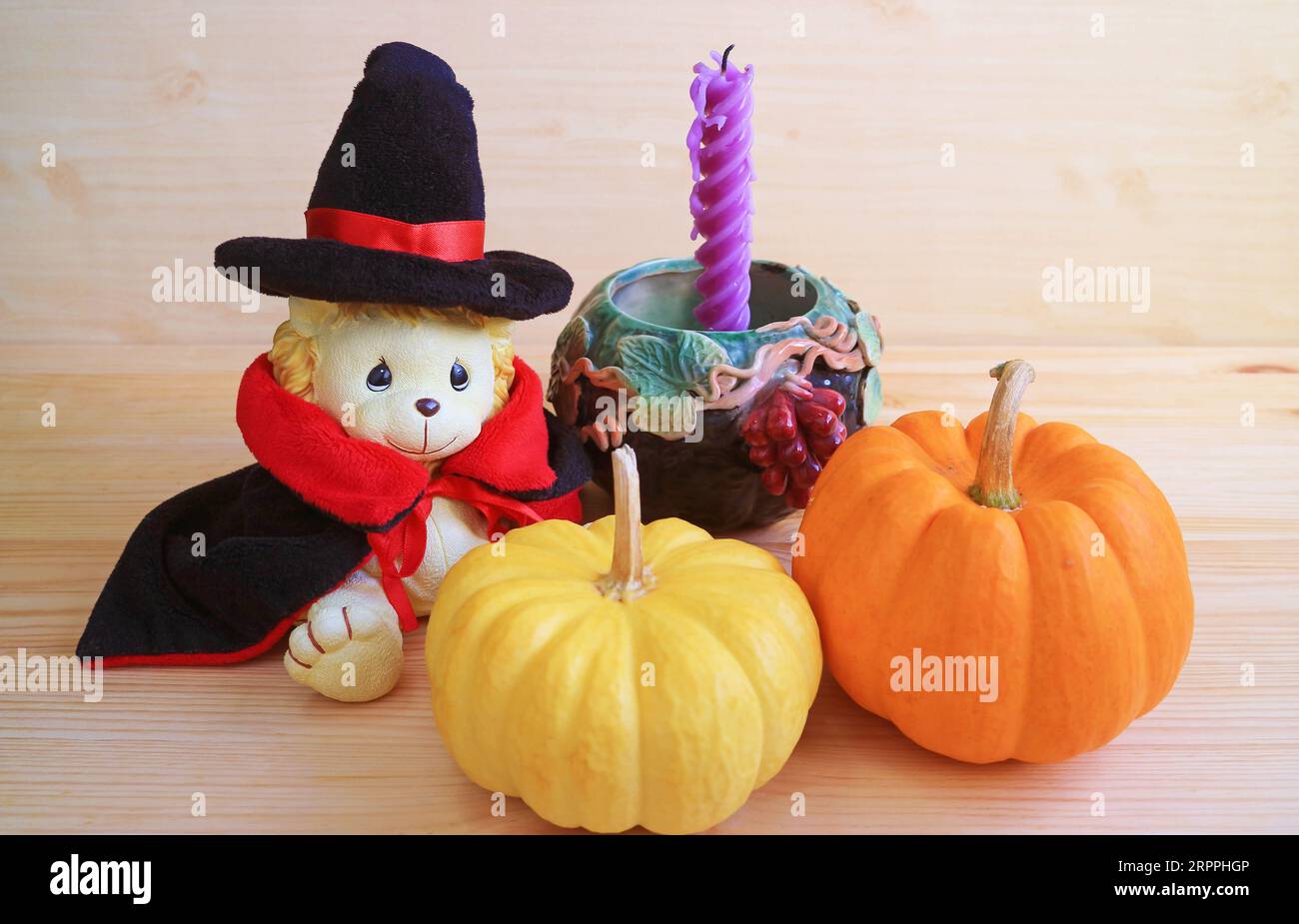 Entzückendes Löwenspielzeug im Zauberkostüm mit Kürbissen und Halloween-Dekoration auf Holzuntergrund Stockfoto