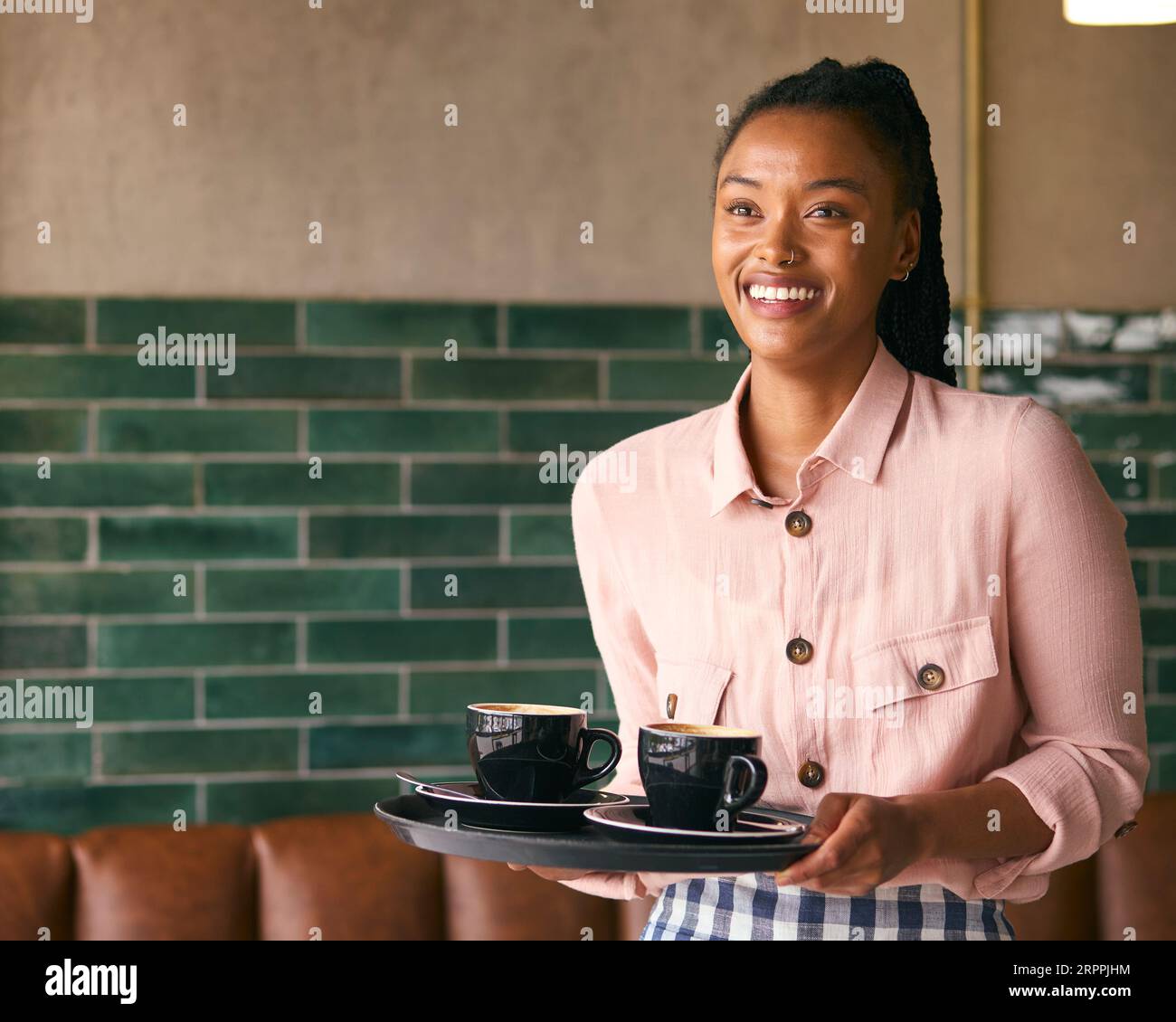 Porträt Der Lächelnden Besitzerin Oder Des Mitarbeiters, Die Tassen Im Café Oder Café Trägt Stockfoto
