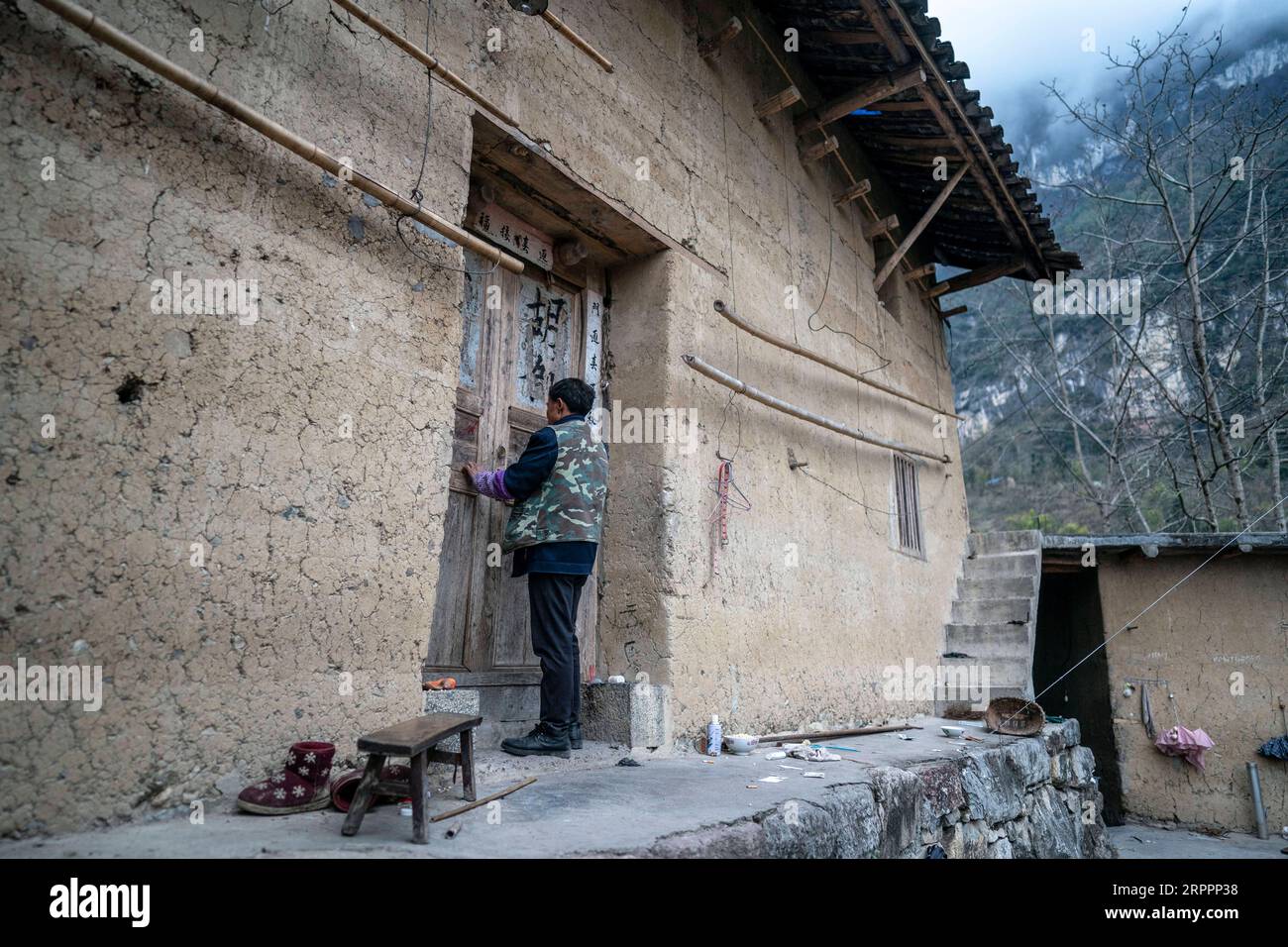 200320 -- KUNMING, 20. März 2020 -- Villager Yan Fugao sperrt sein altes Haus ein, bevor er in das Maojiawan-Umsiedlungsgebiet für verarmte Menschen abreist, im Dorf Luoqiu in der Stadt Daxing im Yongshan County, Provinz Yunnan im Südwesten Chinas, 14. März 2020. Das Dorf Luoqiu liegt tief in den Bergen der Provinz Yunnan im Südwesten Chinas und ist die Heimat von nur dutzenden Haushalten, die sich im Bergtal verteilen. Der Dorfbewohner Yan Fugao und seine Frau Wang Daxiang leben hier seit über 20 Jahren. Die raue Gebirgslandschaft hier hat die wirtschaftlichen Aktivitäten der lokalen Bevölkerung stark eingeschränkt und einige davon verursacht Stockfoto