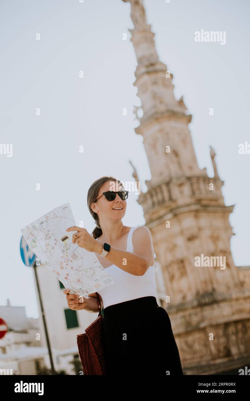 Weibliche Touristen mit einem Stadtplan von der Statue des Heiligen Oronzo in Ostuni, Italien Stockfoto