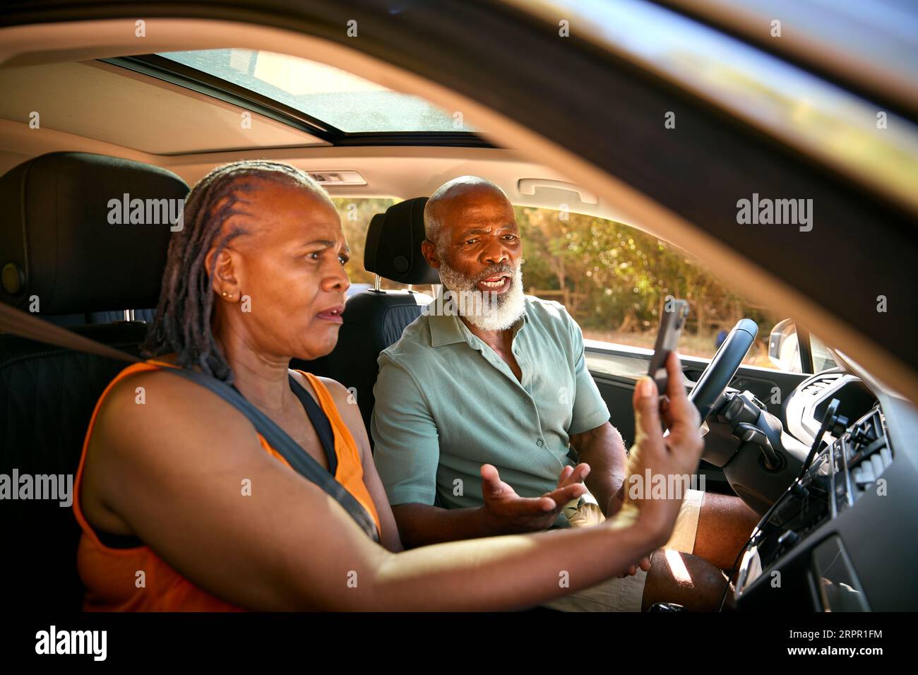 Seniorenpaar im Auto, das sich auf dem Tagesausflug über Wegbeschreibungen auf GPS-Navigationssystem auf dem Mobiltelefon streitet Stockfoto