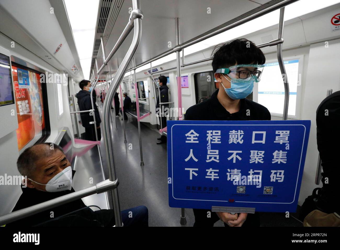 200328 -- WUHAN, 28. März 2020 -- Ein Mitglied der Zugsicherheitsbesatzung hält Ein Plakat, um die Passagiere daran zu erinnern, dass sie den QR-Code für die Registrierung eines echten Namens scannen und Masken in einem Zug entlang der Wuhan Metro Line 2 in Wuhan, Provinz Hubei, tragen, 28. März 2020. Sechs U-Bahn-Linien in Wuhan nahmen den Betrieb ab Samstag wieder auf, ein neues Zeichen dafür, dass das Leben in der am stärksten betroffenen Stadt allmählich wieder normal wird. Passagiere müssen den QR-Code für die Registrierung mit dem richtigen Namen scannen und die Temperatur vor der U-Bahn überprüfen. Jeder Zug ist mit einem Zugsicherungspersonal ausgestattet, das gui unterstützt Stockfoto