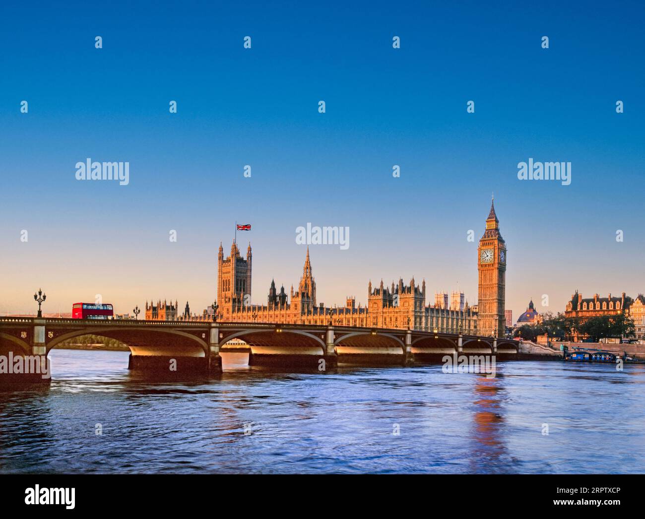 Houses of Parliament Westminster UK mit der Union Jack Flagge, beleuchtet bei Sonnenaufgang bei Sonnenaufgang, roter Londoner Bus auf der Westminster Bridge. Themse bei Flut von South Bank London UK. Reiseziel der Landschaft von London Stockfoto