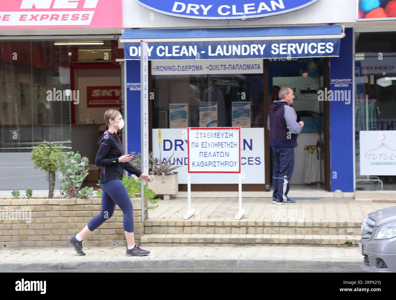 200504 -- NICOSIA, 4. Mai 2020 -- Eine Frau mit Gesichtsmaske läuft am 4. Mai 2020 an einer Wäscherei in Nicosia, Zypern vorbei. Zypern hat seine Wirtschaft am Montag ankurbelt, indem es 25.000 Einzelhandelsgeschäften und dem Baugewerbe nach einer sechswöchigen Coronavirus-Sperrung die Wiederaufnahme des Betriebs ermöglichte. ZYPERN-NIKOSIA-COVID-19-ECONOMY-KICK-STARTING ZHANGXBAOPING PUBLICATIONXNOTXINXCHN Stockfoto