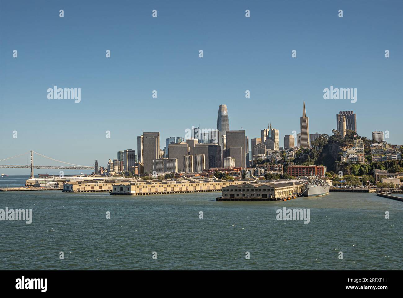 San Francisco, CA, USA - 13. Juli 2023: Urbandschungel und Wolkenkratzer des Finanzviertels hinter Docks und Lagerhallen des Hafens unter blauem Himmel. Oakland Stockfoto