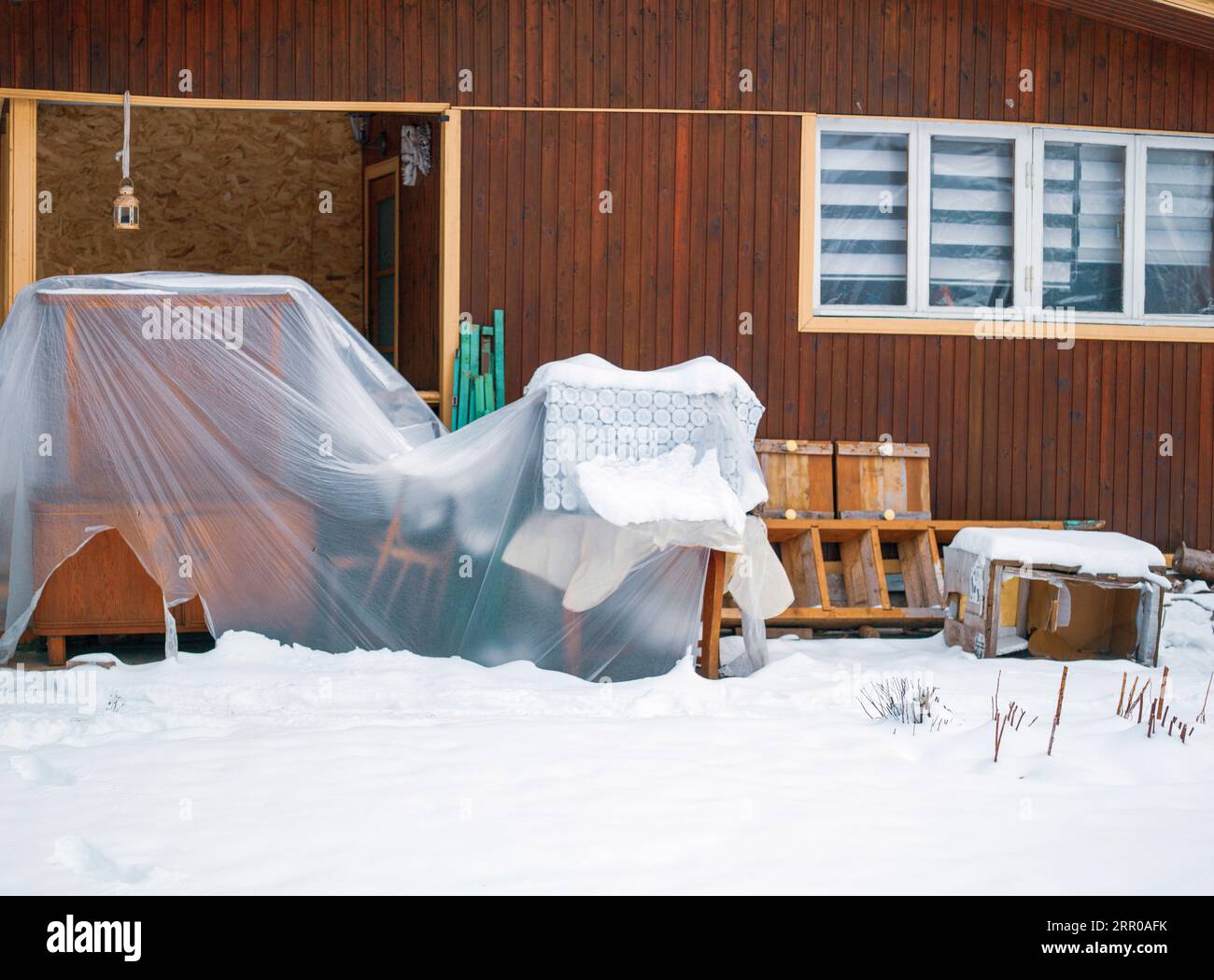 Alt, bedeckt mit Cellophanmöbeln, die vor einem Haus stehen, Winterszene Stockfoto