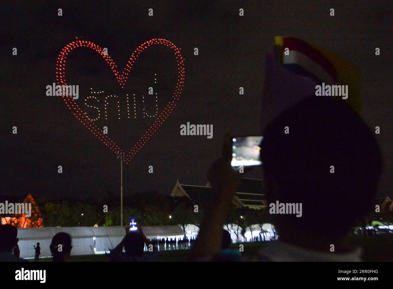 200813 -- BANGKOK, 13. August 2020 -- Menschen beobachten eine Drohnenvorstellung während einer Veranstaltung zum 88. Geburtstag der thailändischen Königin Mutter Sirikit in der Nähe des Großen Palastes in Bangkok, Thailand, 12. August 2020. THAILAND-BANGKOK-KÖNIGIN MUTTERGEBURTRACHENXSAGEAMSAK PUBLICATIONxNOTxINxCHN Stockfoto