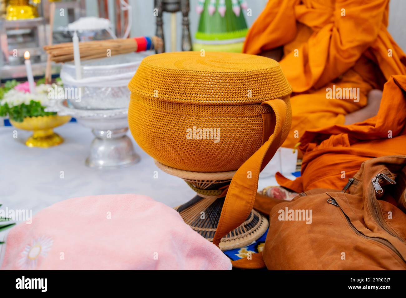 Eine Almosenschüssel aus Metall, die mit goldorangefarbenem Tuch bedeckt ist, um Nahrung von Laien und Menschen zu erhalten, die an den Buddhismus glauben. Stockfoto
