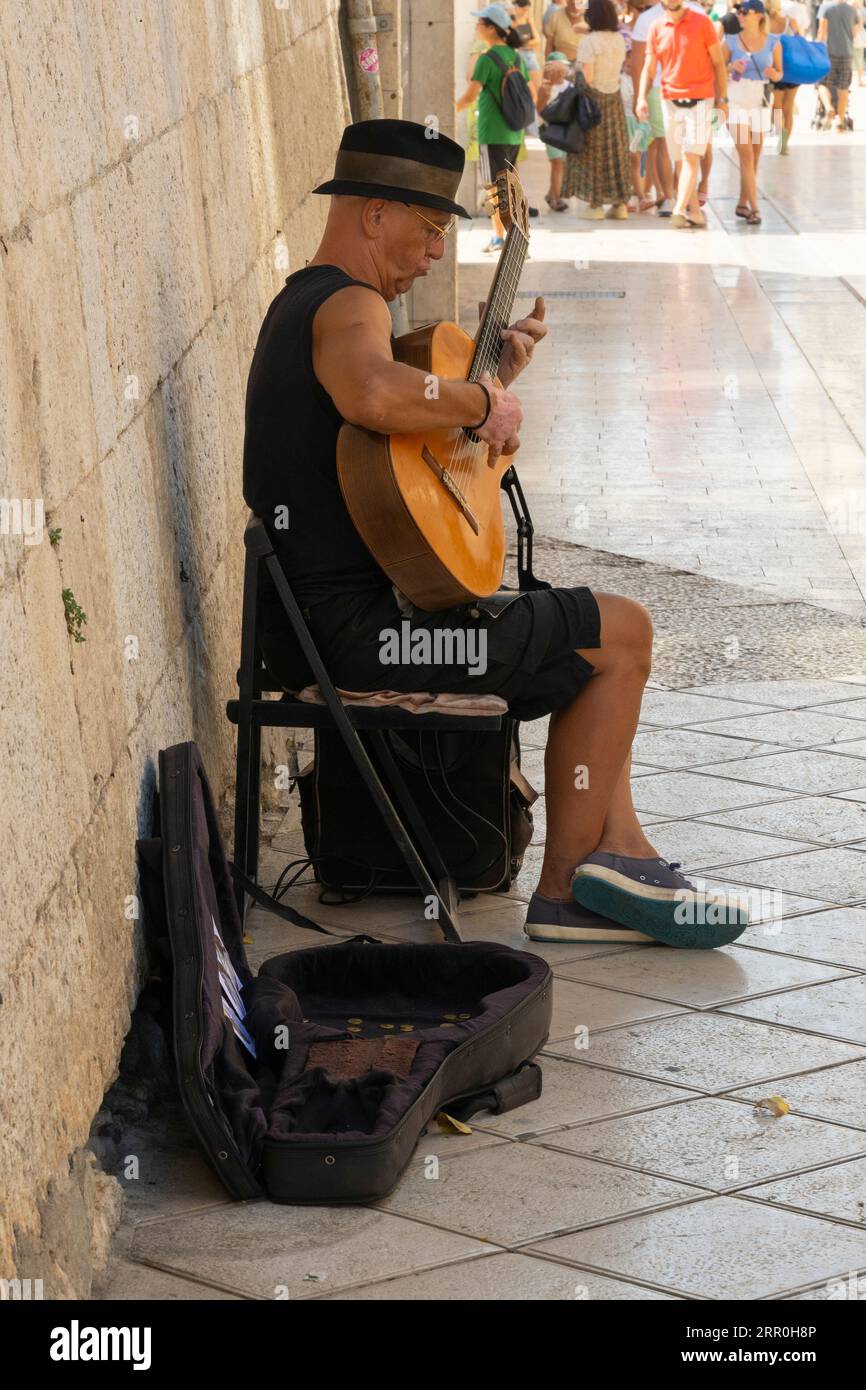 Kroatien Split Stadt Hafen Altstadt Busker reifer Mann 6-saitige Gitarre lokale Musik Gesang Hut sitzender Schatten Gitarrenkasten DVDs Spenden lose Münzen Stockfoto