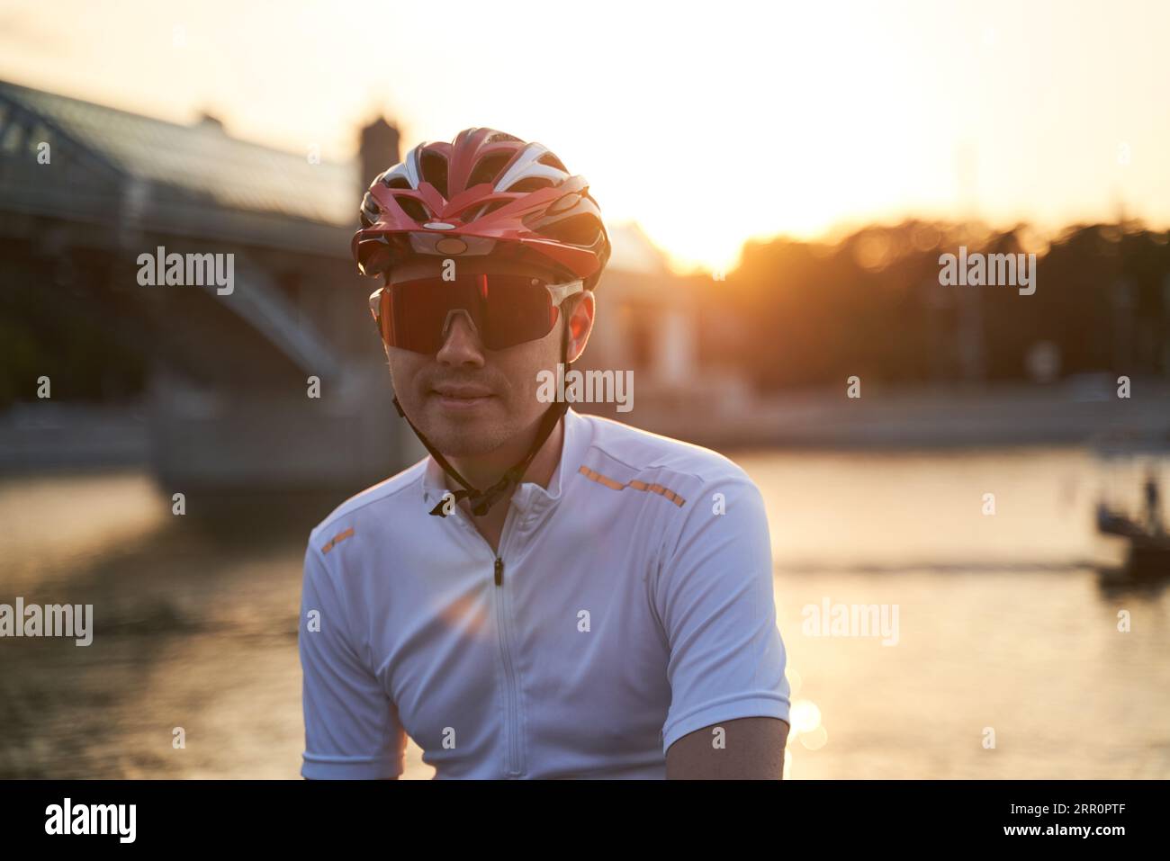 Der Mann trägt einen Schutzhelm, eine Sonnenbrille und Sportkleidung während der abendlichen Fahrt in der Stadt. Nahaufnahme Stockfoto