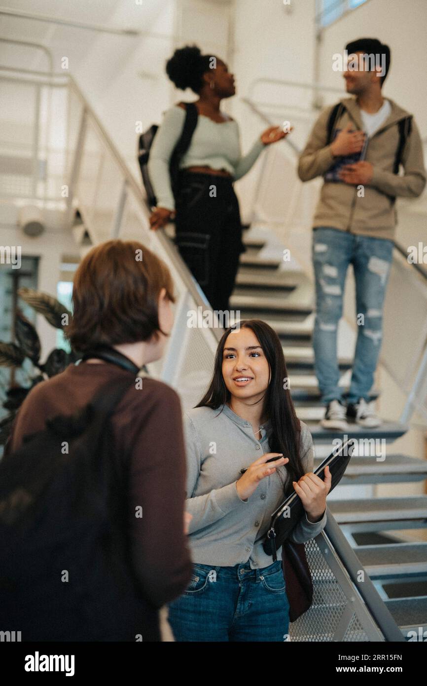 Multirassische Studentinnen diskutieren über Treppenaufgänge an der Universität Stockfoto