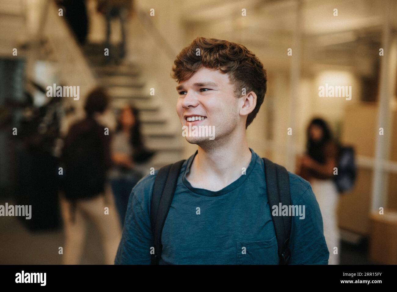 Glücklicher junger männlicher Student, der an der Universität steht Stockfoto