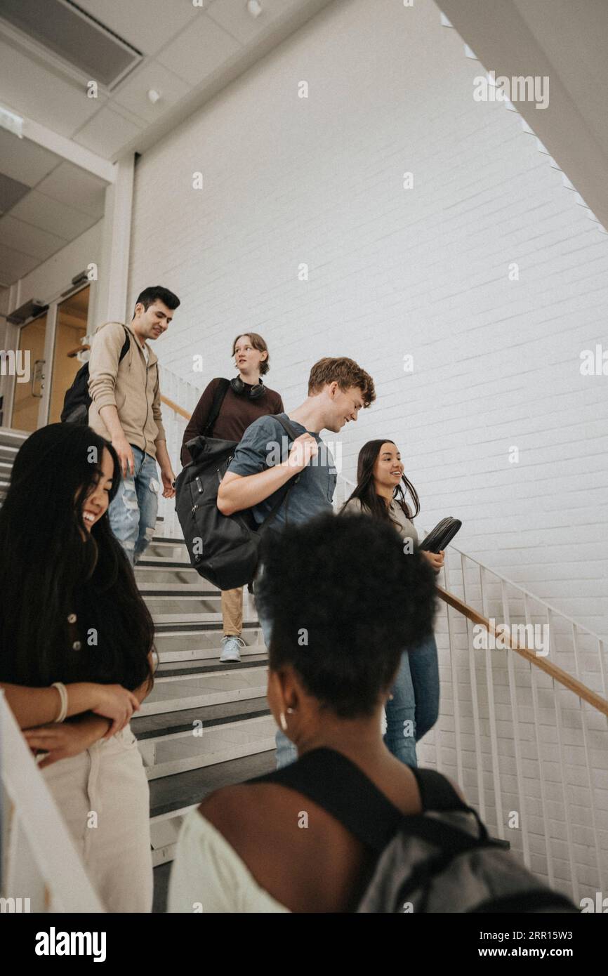 Glückliche männliche und weibliche multirassische Studenten auf Treppen in der Universität Stockfoto