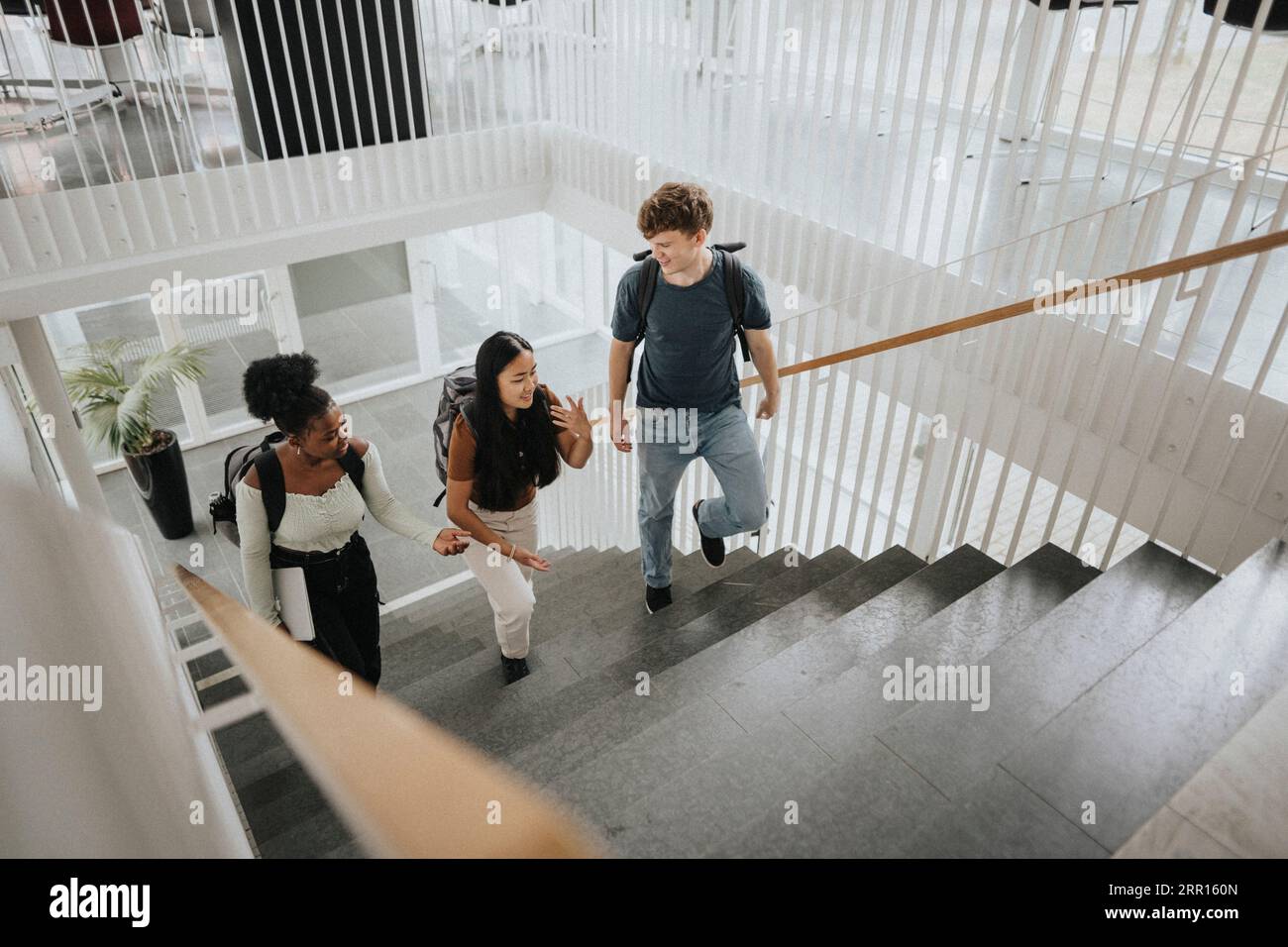 Hochwinkelansicht von multirassischen männlichen und weiblichen Studenten, die auf Stufen in der Universität aufsteigen Stockfoto