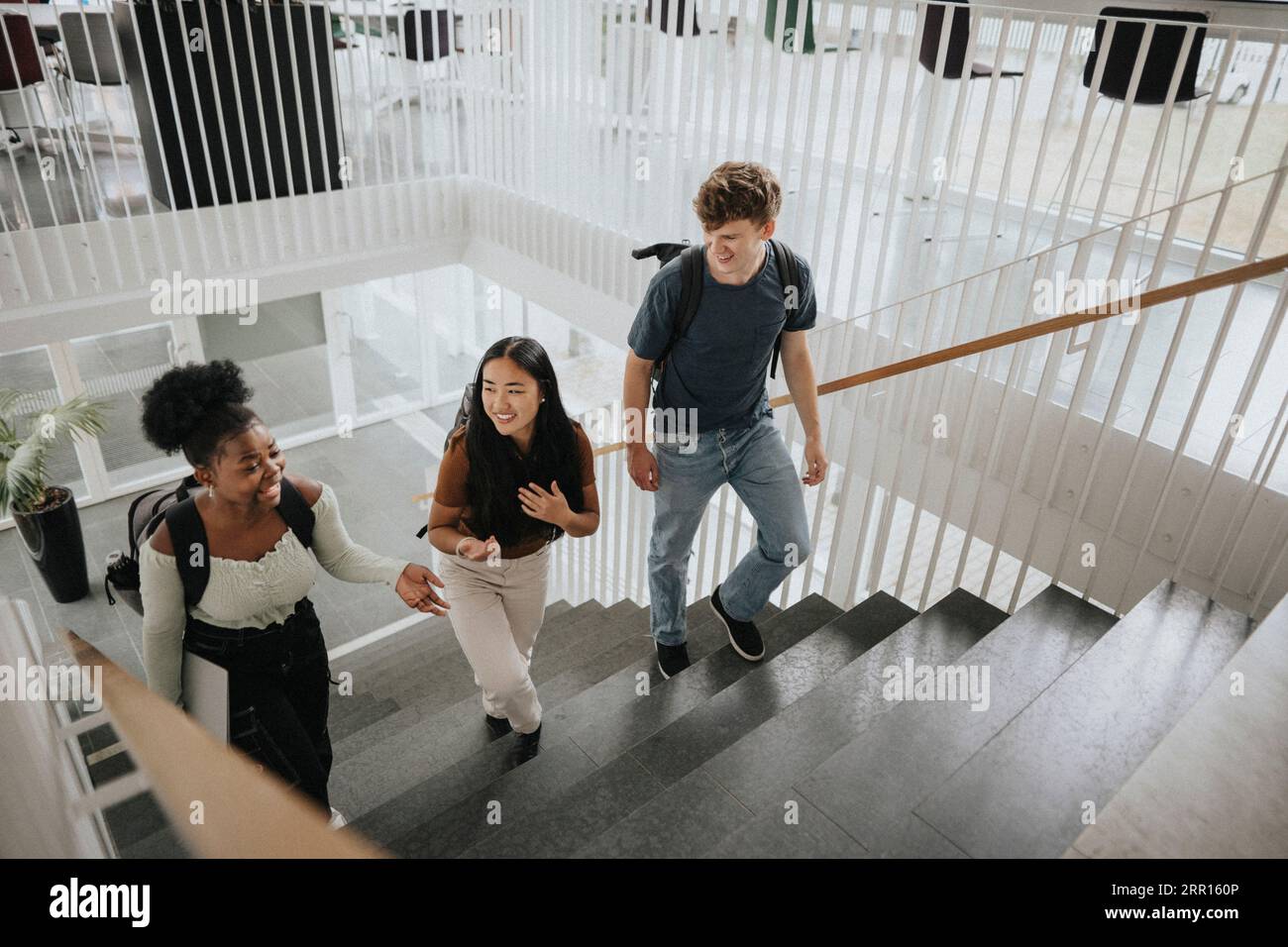 Blick auf glückliche multirassische Studenten, die auf Stufen in der Universität aufsteigen Stockfoto