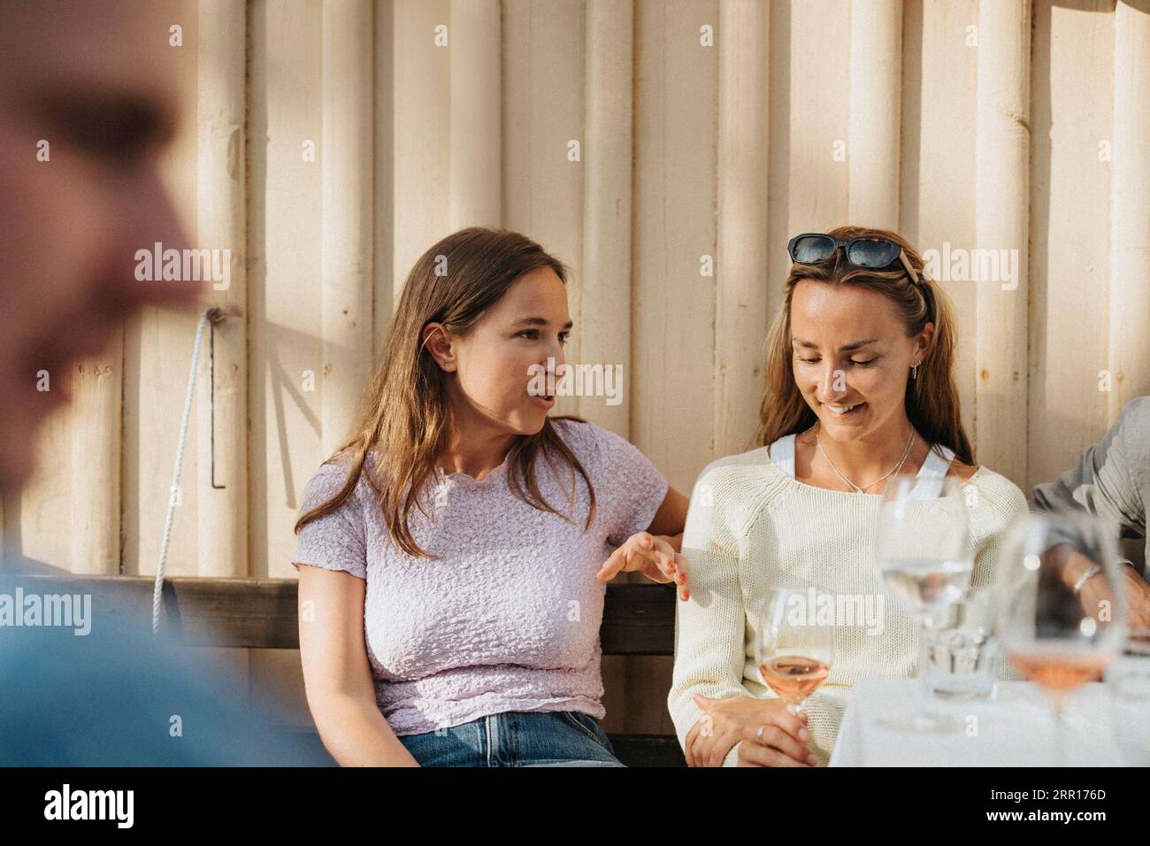 Junge Frau, die mit einer Freundin während einer Dinnerparty im Café spricht Stockfoto
