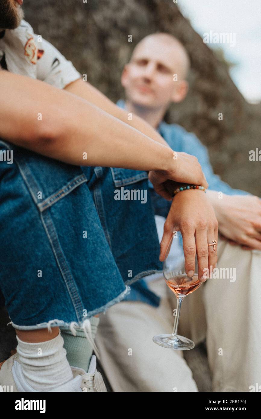 Junger Mann, der Wein im Glas hält, während er mit einem Freund sitzt Stockfoto
