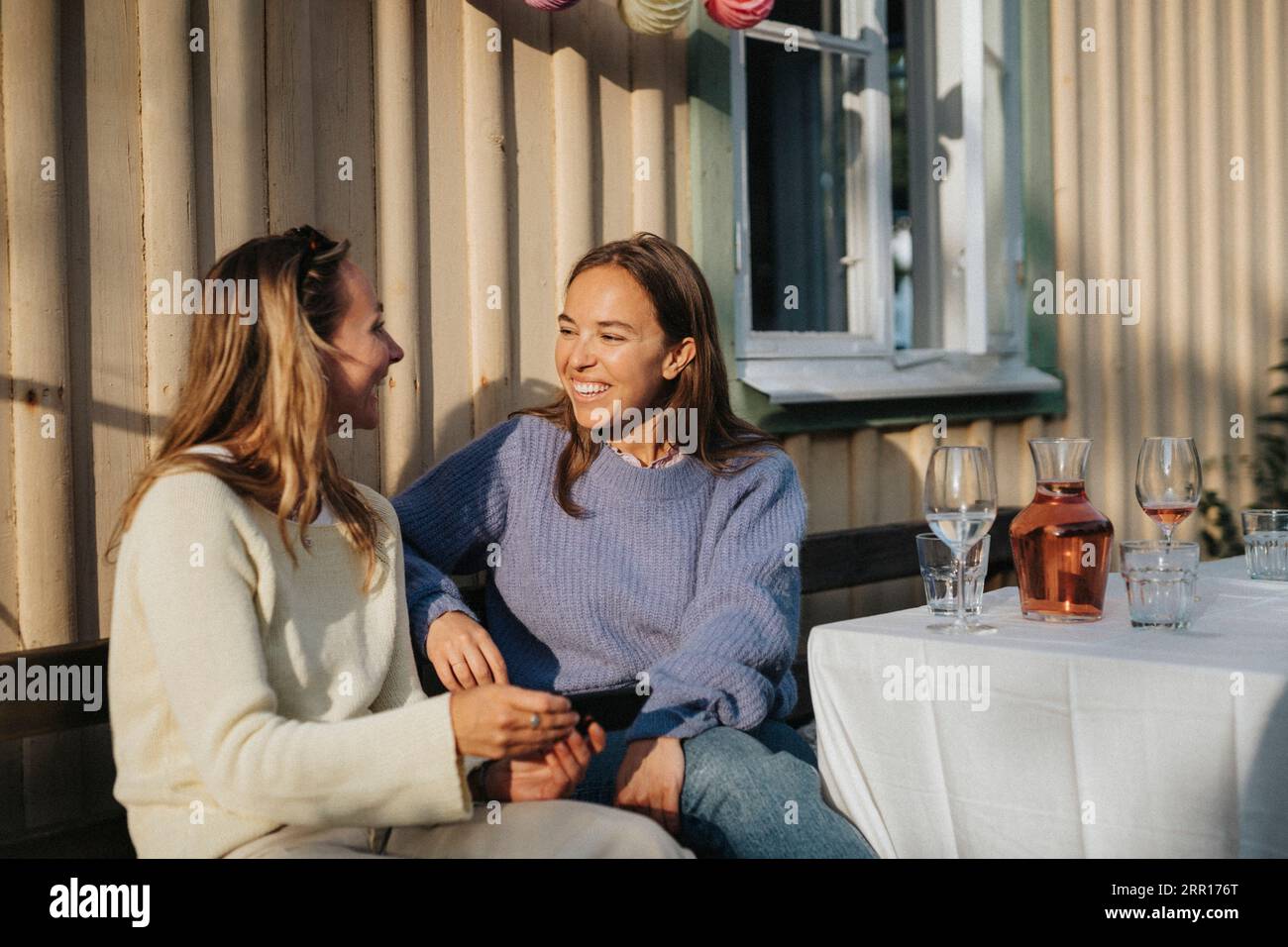 Glückliche junge Frauen, die während einer Dinnerparty im Café miteinander reden Stockfoto