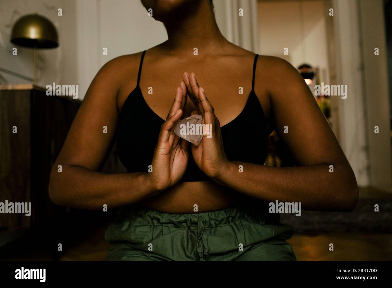 Mittelteil einer Frau, die Kristall hält, während sie zu Hause trainiert Stockfoto