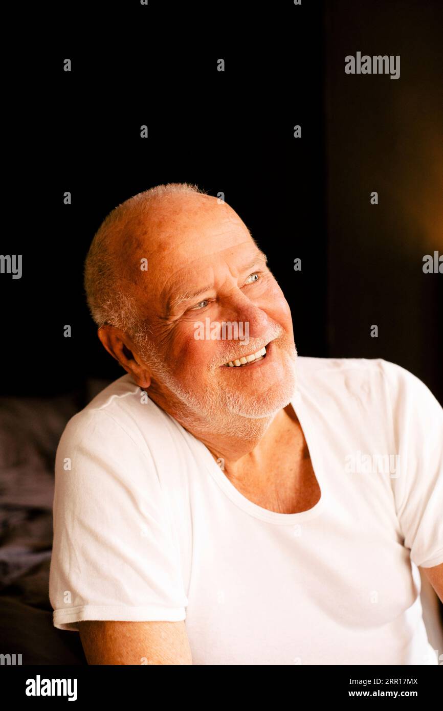 Glücklicher, nachdenklicher älterer Mann, der zu Hause sitzt Stockfoto