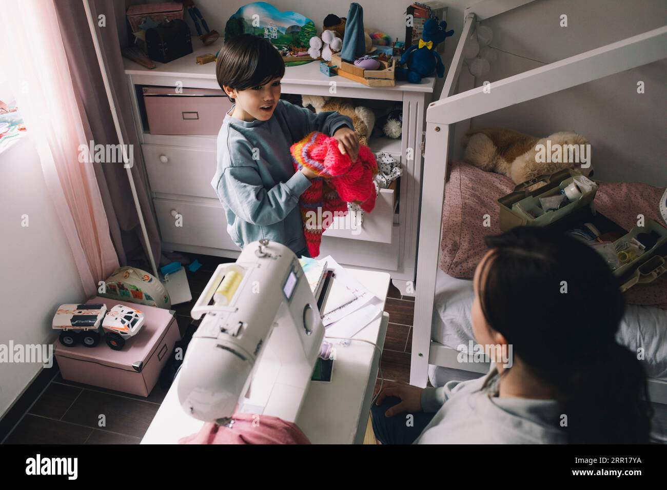 Blick auf den Jungen mit warmer Kleidung, der zu Hause mit der Mutter spricht Stockfoto