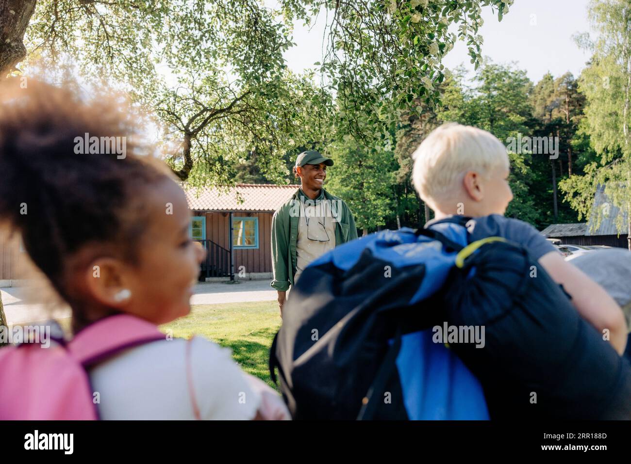 Lächelnder männlicher Lagerberater mit Kindern im Sommerlager Stockfoto