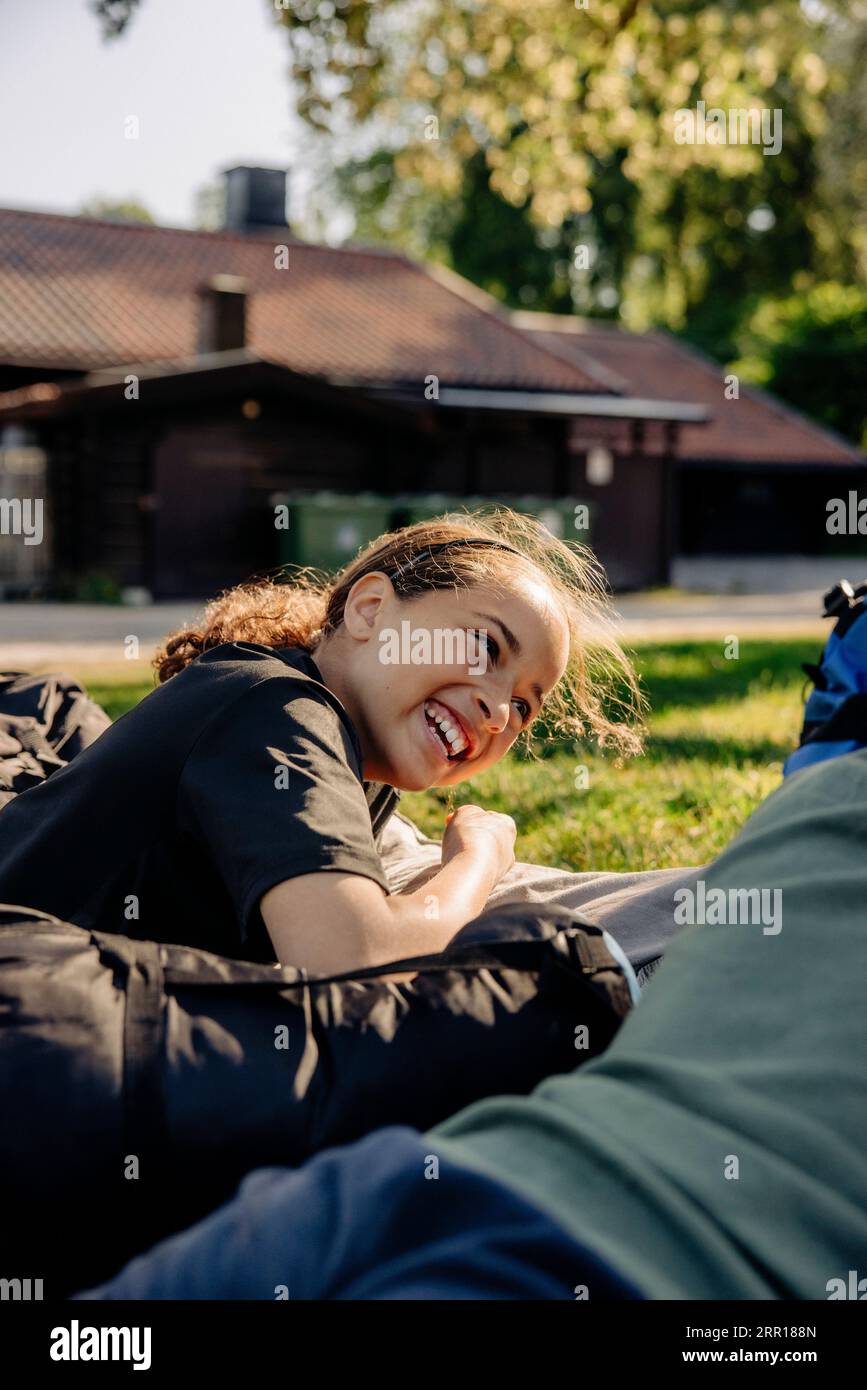 Seitenansicht des fröhlichen Mädchens, das beim Liegen im Sommercamp lachte Stockfoto