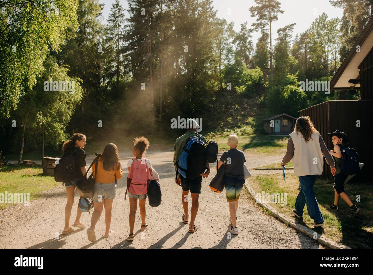 Rückansicht der Kinder, die auf dem Wanderweg mit den Betreuern im Sommercamp gehen Stockfoto