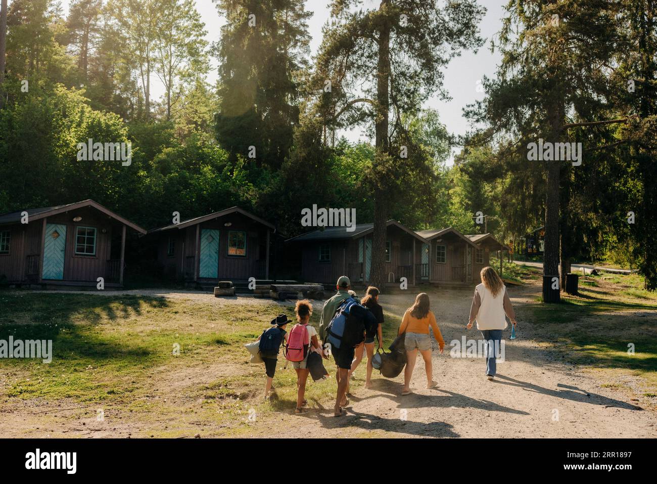 Kinder laufen mit Ratgebern in Richtung Hütten im Sommercamp Stockfoto