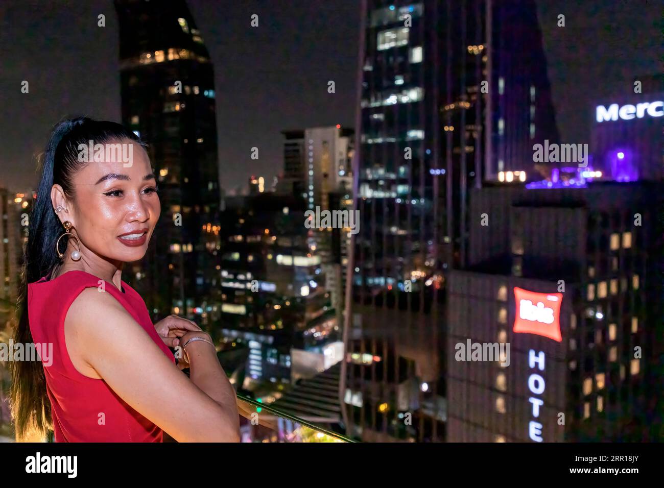 Thai Dame auf Balkon in der Dachbar mit Bangkok City Skyline in der Nacht, Thailand Stockfoto