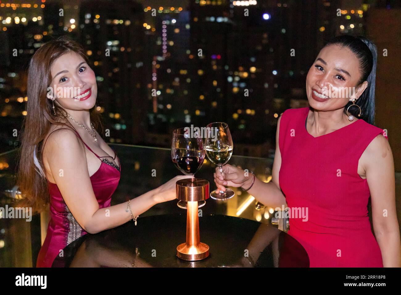 Thai-Damen trinken Wein in der Dachbar im Stadtzentrum in Bangkok, Thailand Stockfoto