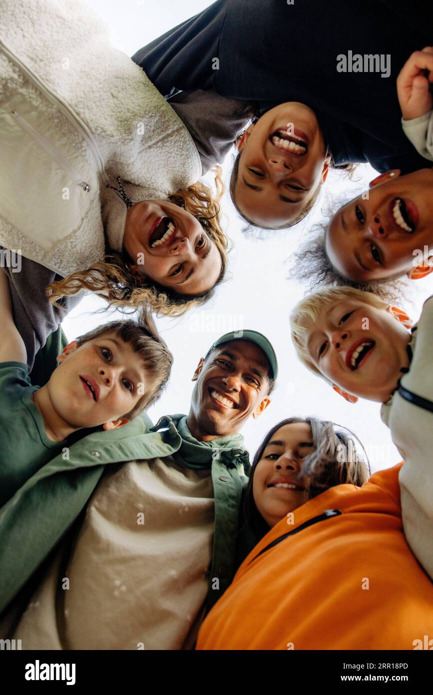 Direkt unter dem Bild von Kindern, die sich mit Ratgebern gegen den Himmel zusammenkuscheln Stockfoto