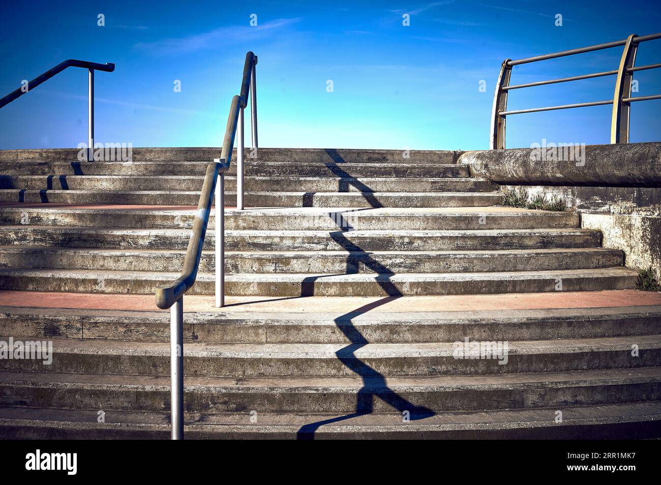 Unregelmäßiger Schatten von Geländern auf Steintreppen auf der Blackpool South Promenade Stockfoto