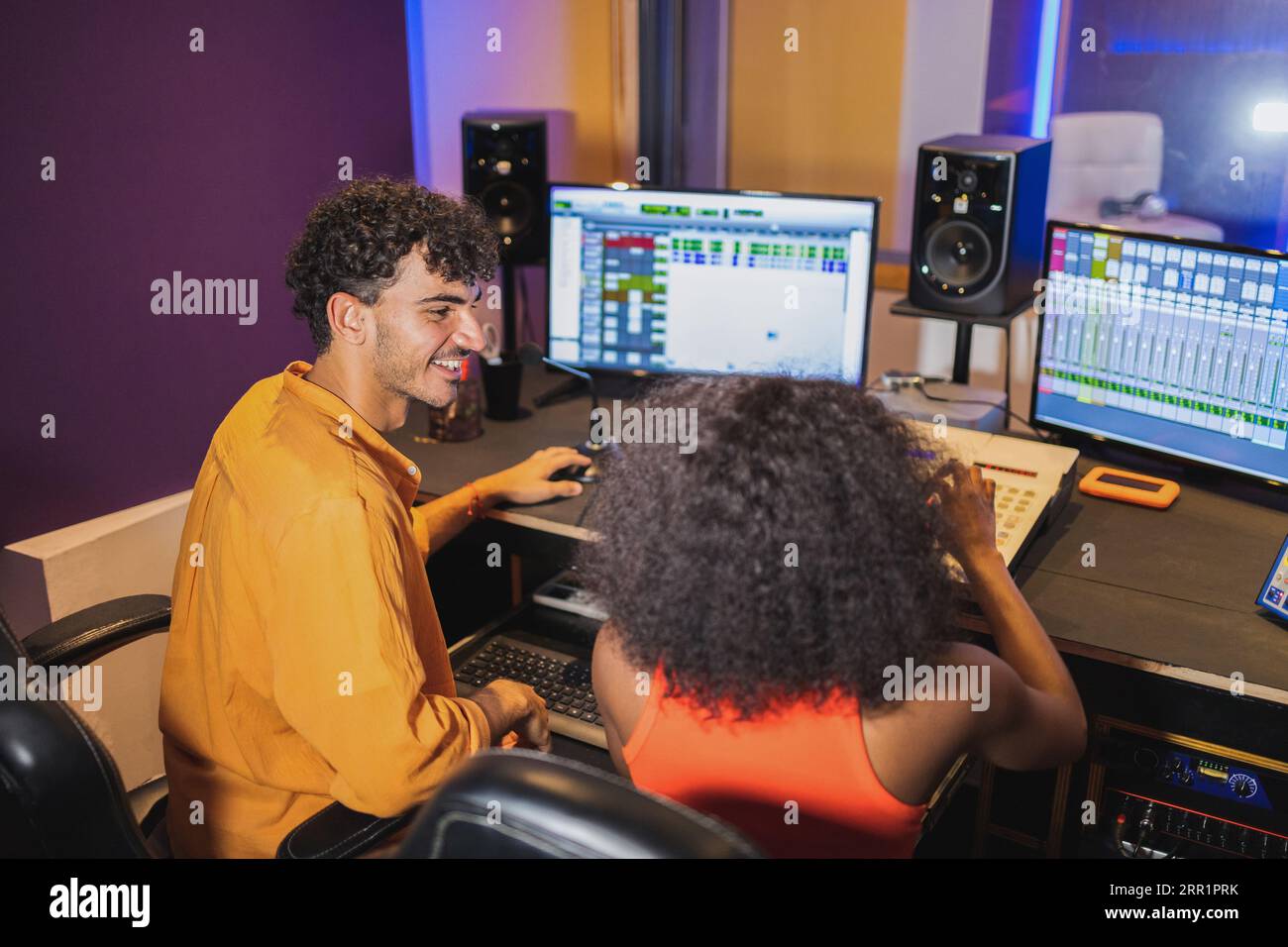 Männlicher Toningenieur und afroamerikanische Sängerin, die im Kontrollraum mit Computer-Sound-Software und Mischpult aufgenommen wurde Stockfoto