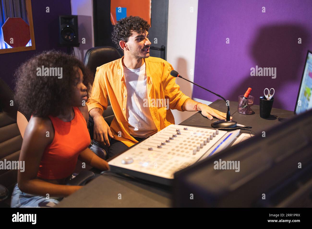 Männlicher Toningenieur und afroamerikanische Sängerin, die im Kontrollraum mit Computer-Sound-Software und Mischpult aufgenommen wurde Stockfoto