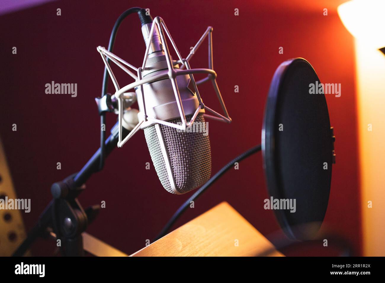 Professionelle Ausstattung mit einstellbarem Mikrofon auf Stange mit zwei Bildschirm-Pop-Filter für die Aufnahme von Podcasts in unscharfen Studio-Farblichtern Stockfoto